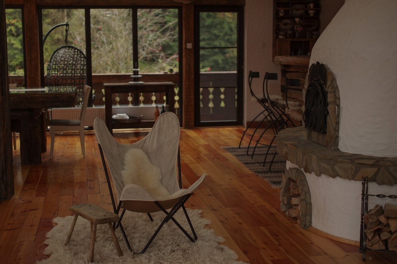 Comfy chair on fur rug next to fireplace in cozy room at Biovaleputna guest house